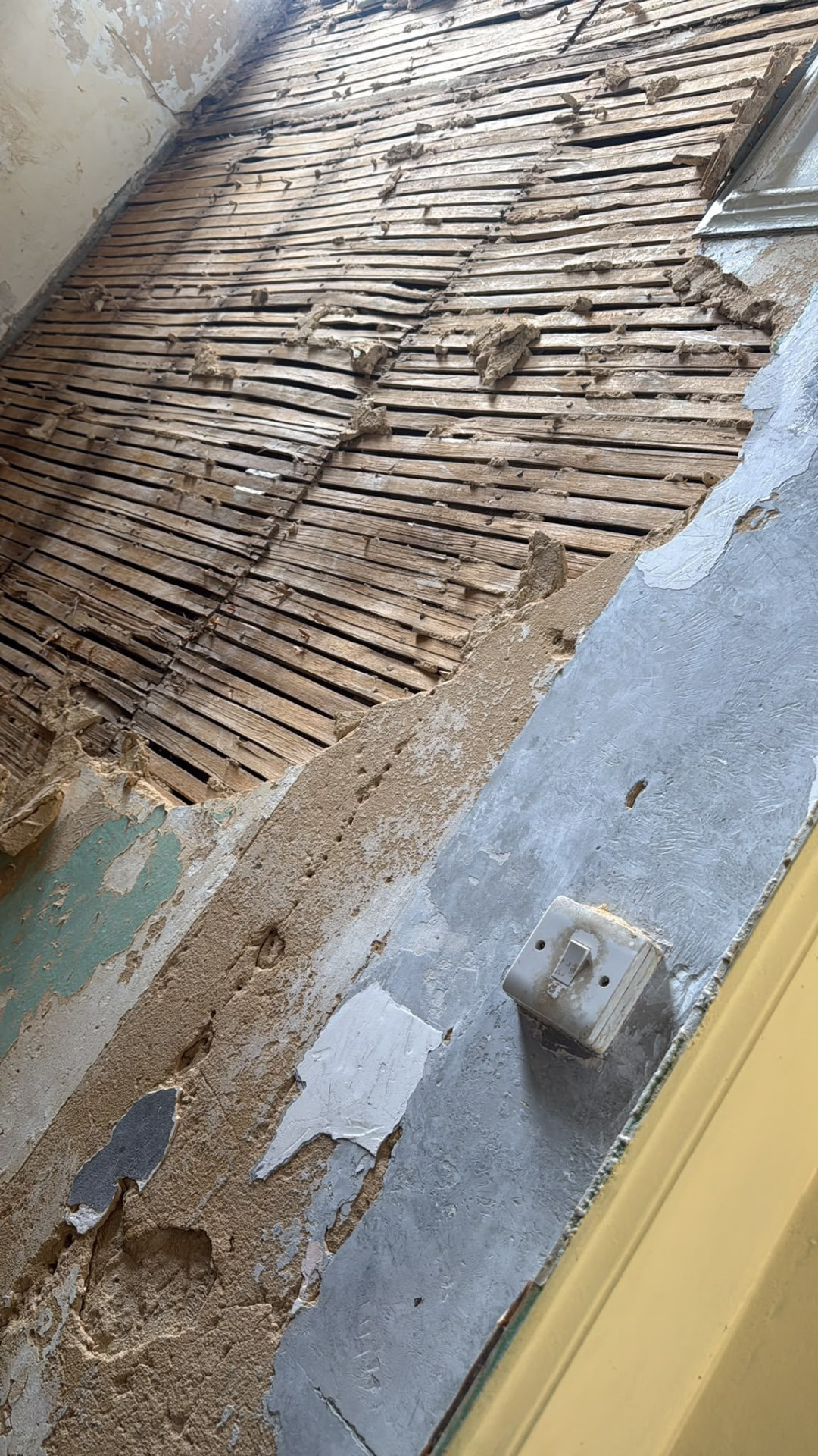 Wall stripped back to wooden lath and plaster during a strip-out in Wimborne, Dorset