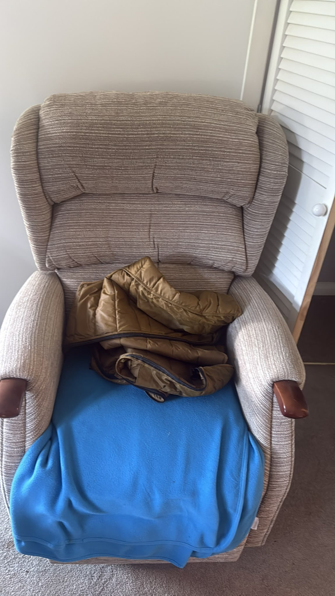 Armchair with clothing and covers awaiting house clearance in Wimborne, Dorset