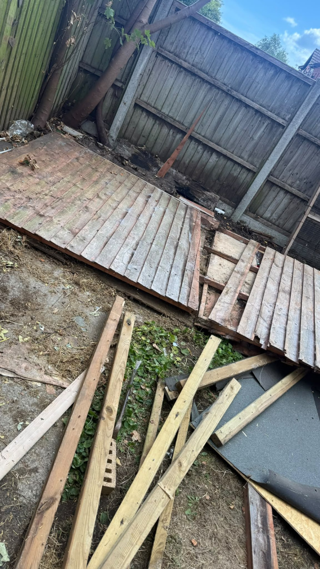 Dismantled shed floor boards in a garden during demolition in Wimborne, Dorset