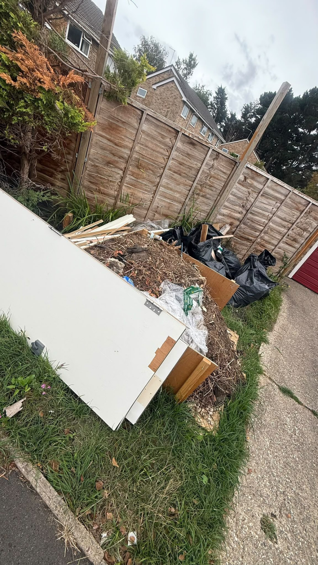 Garden debris and bulky waste beside a driveway awaiting collection in Wimborne, Dorset