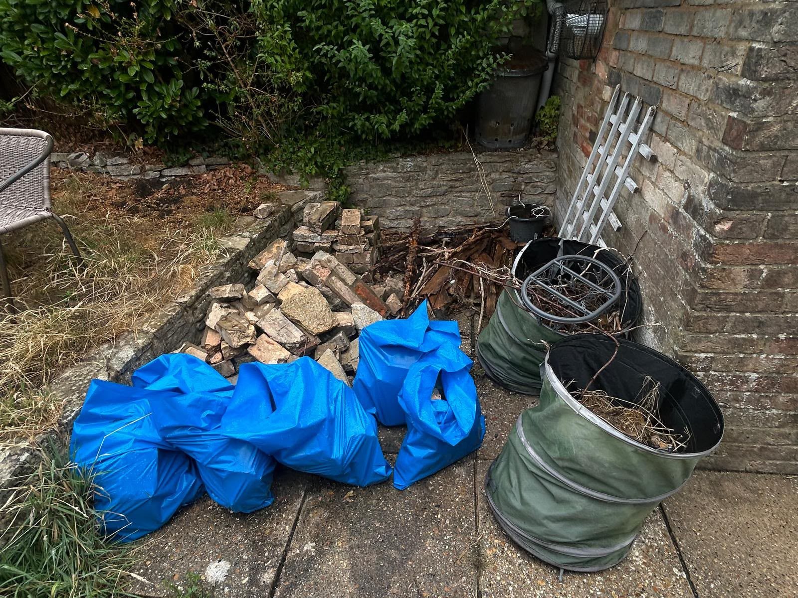 Rubble and bagged waste in a garden corner awaiting collection in Wimborne, Dorset