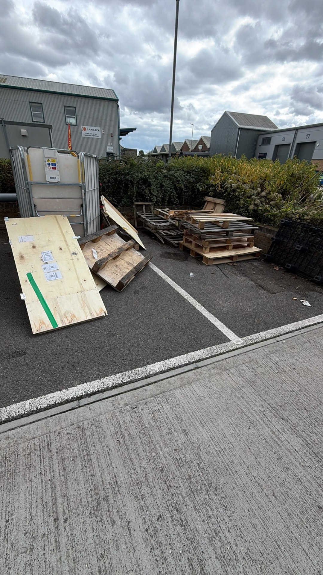 Pallets and wood panels beside commercial units awaiting waste removal in Wimborne, Dorset